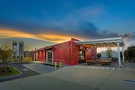 A brewery building with outdoor tables at dusk in Ivanhoe Village